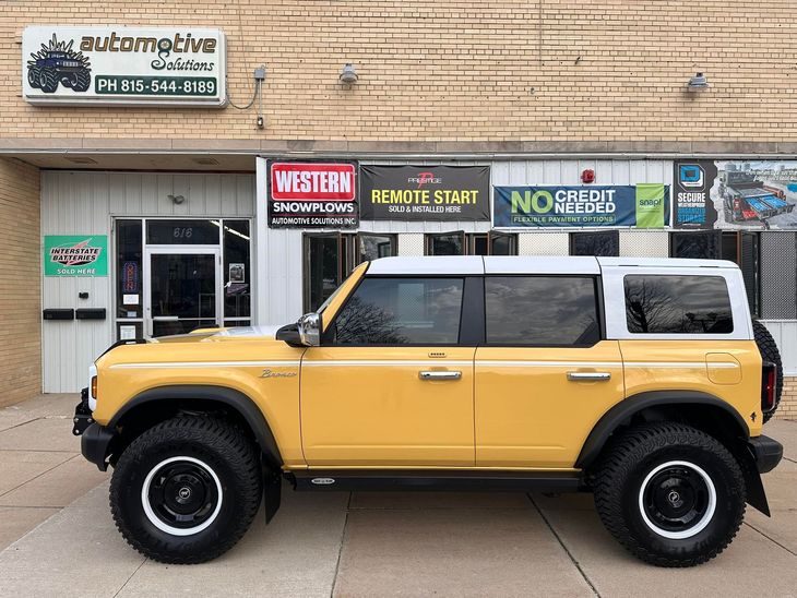 Yellow lifted SUV parked in front of storefronts on a city street