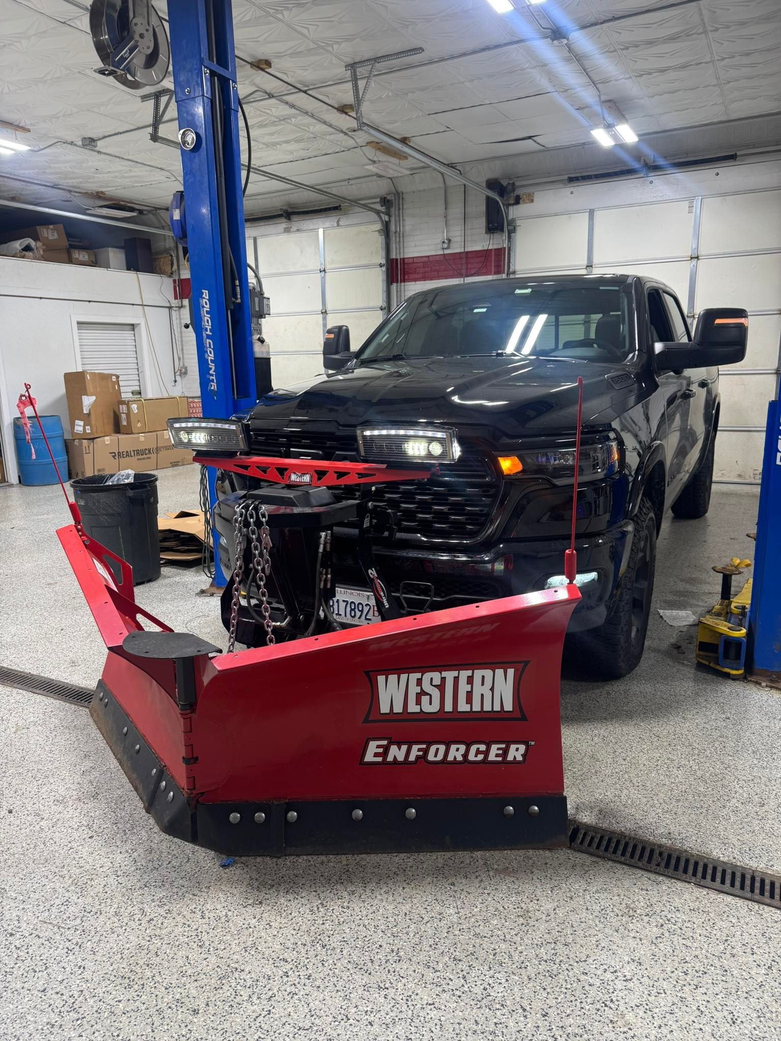 Black pickup truck with a Western Enforcer snowplow in a garage workspace