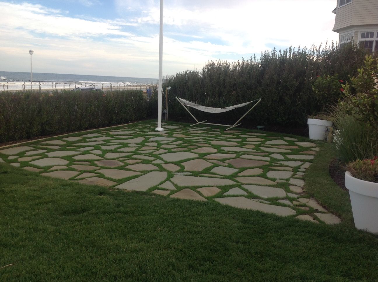 A hammock is sitting on a patio next to a flag pole.