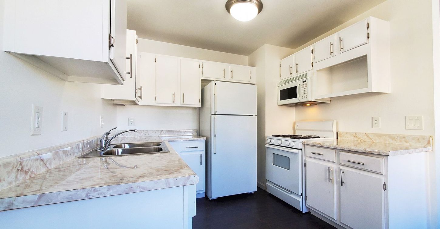 A kitchen with white cabinets and a white refrigerator