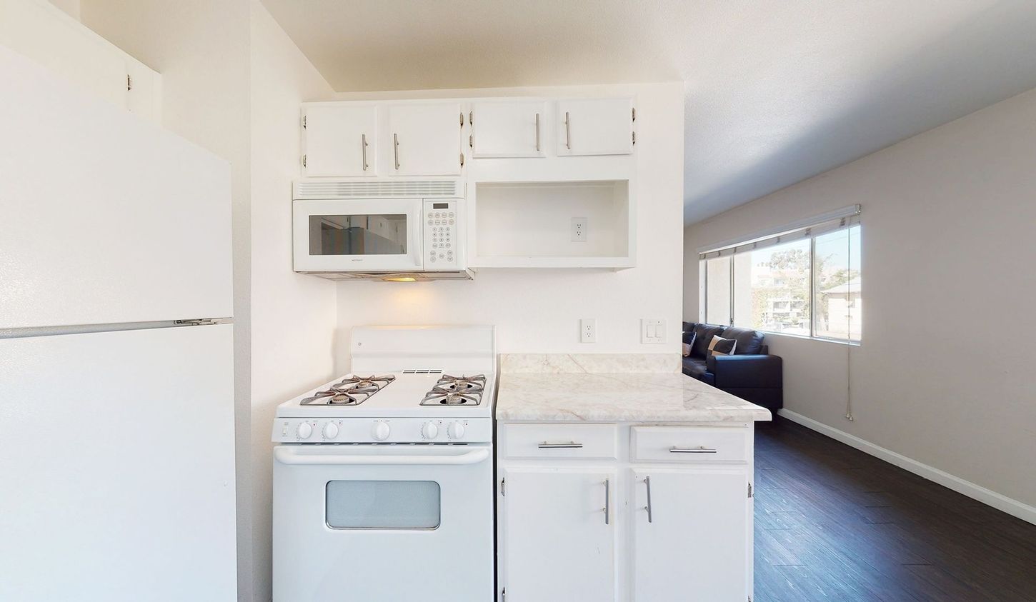 A kitchen with a stove , microwave and refrigerator