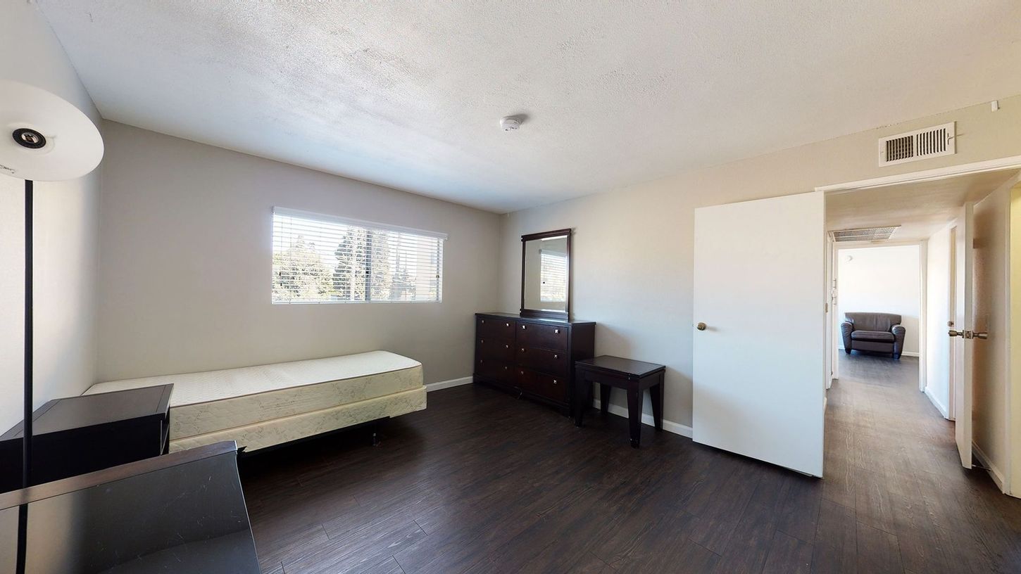 A bedroom with a bed , dresser , mirror and lamp.