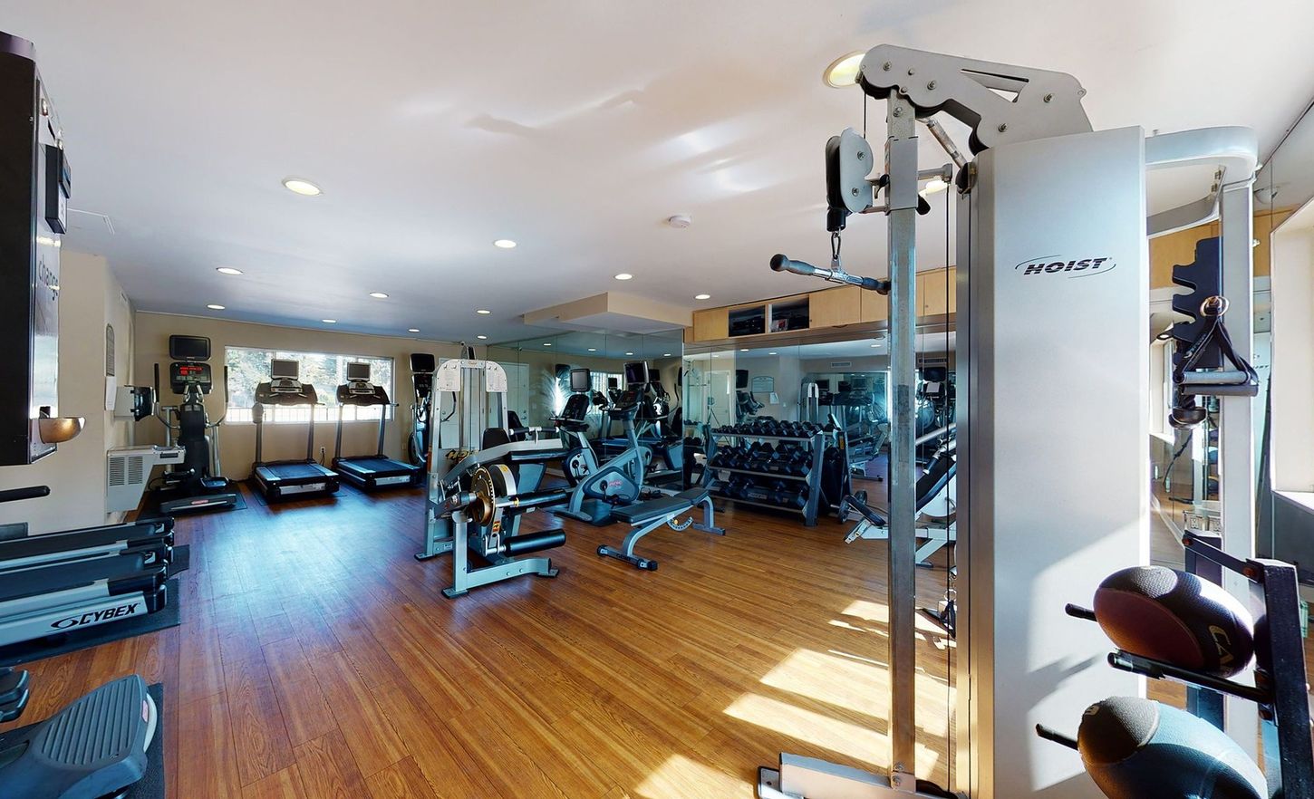 A large gym with a lot of equipment and a wooden floor.