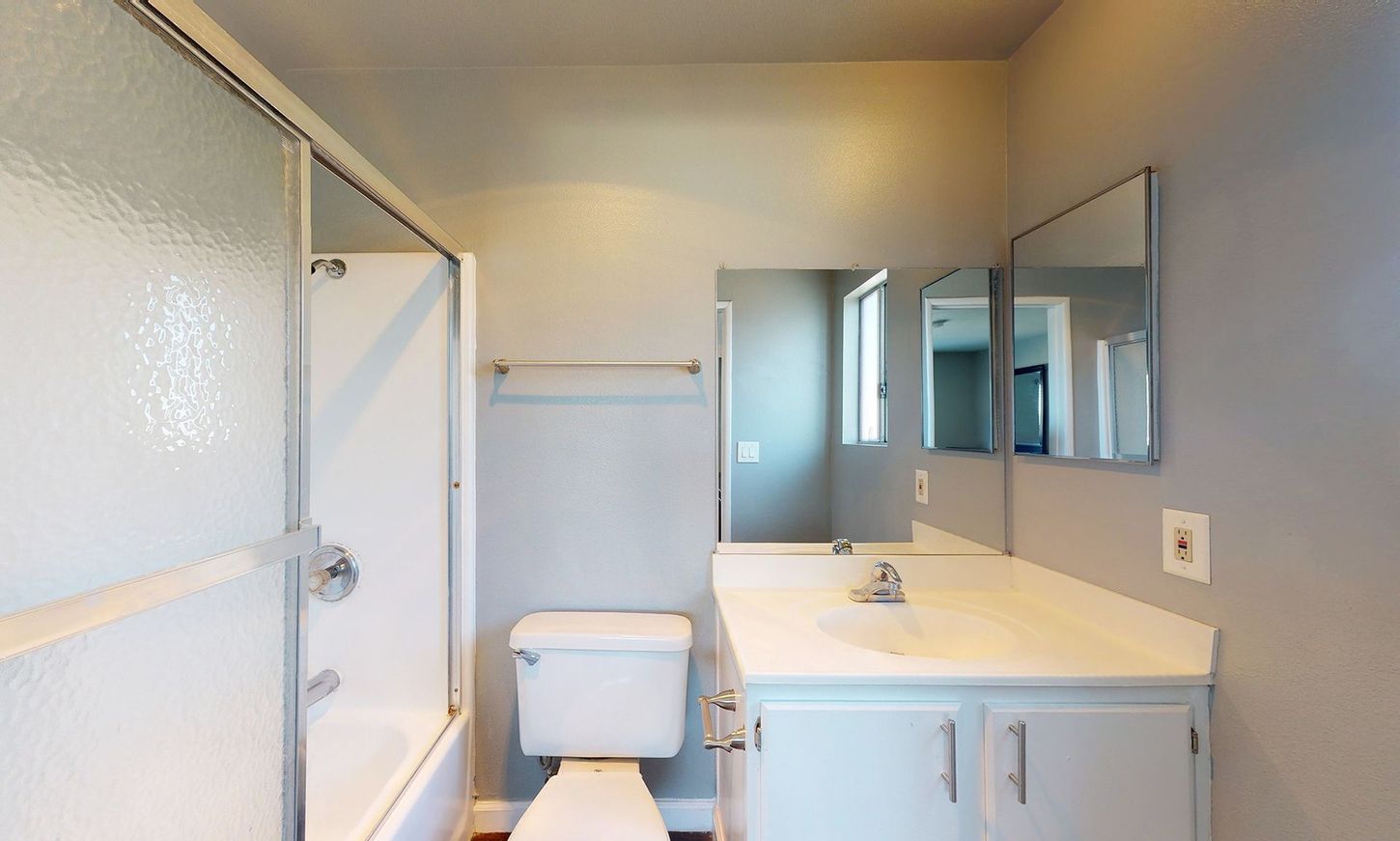 A bathroom with a toilet , sink , shower and mirror.