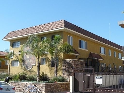 A yellow building with a brown roof and a bicycle parked in front of it
