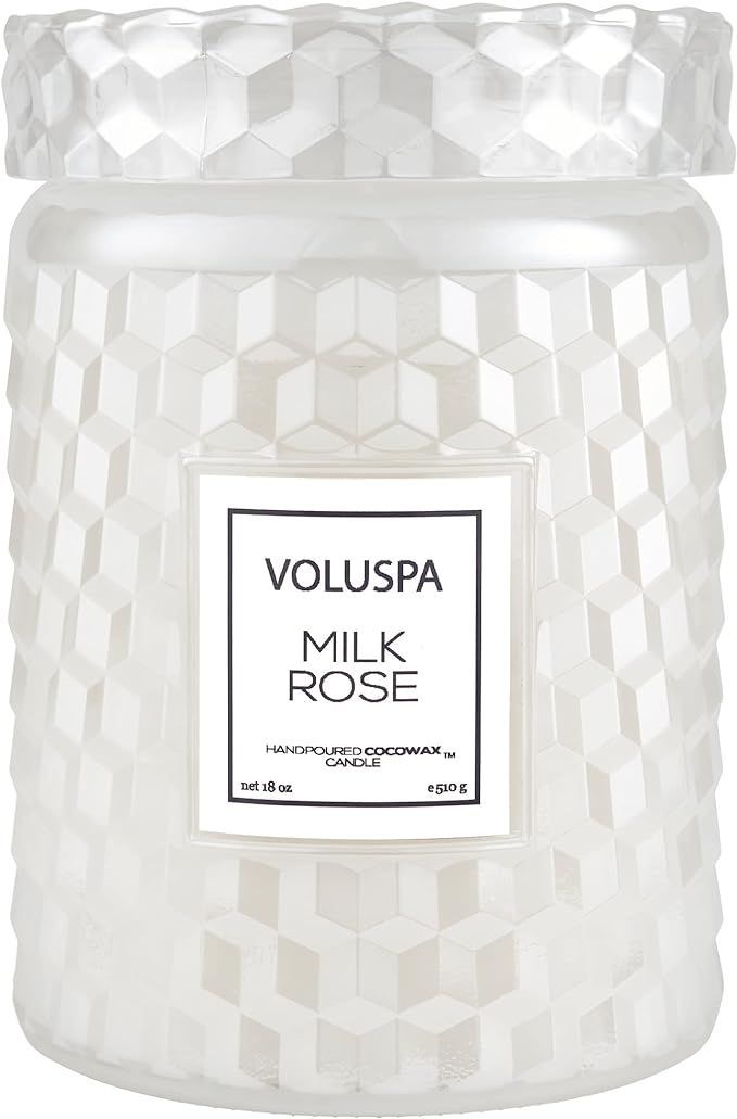 a white candle with a label that says milk rose on it
