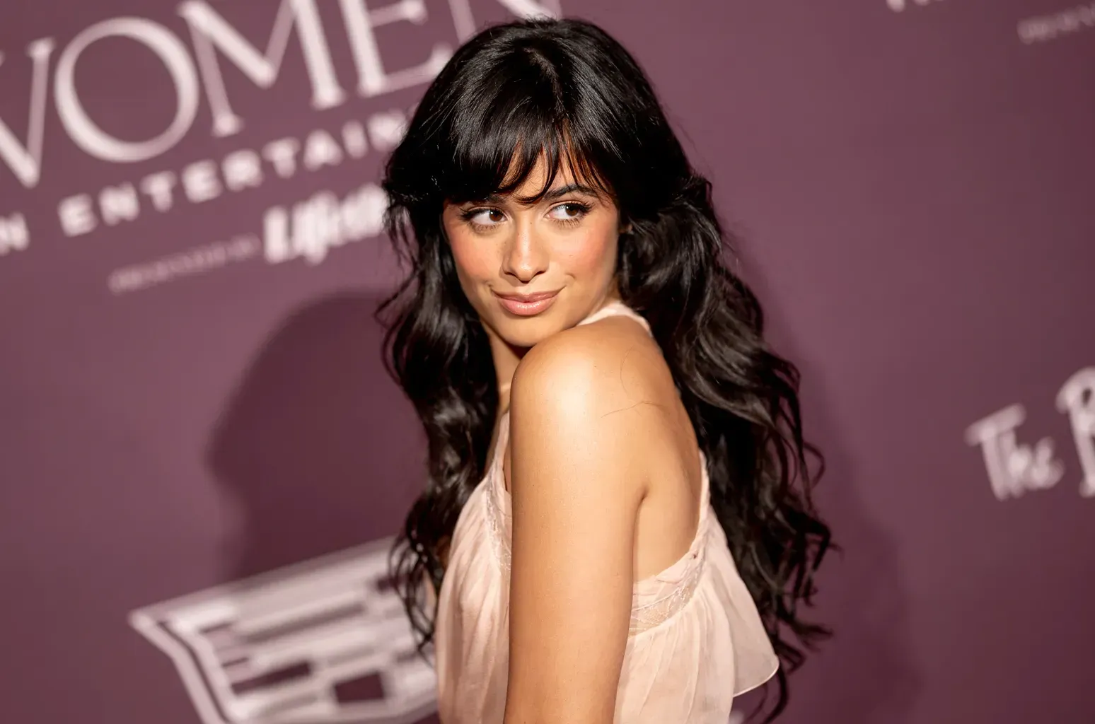 a woman in a pink dress is standing on a purple carpet with the word vome on it