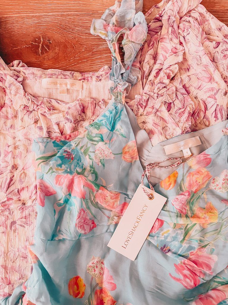 two dresses with tags on them are sitting on a wooden table .
