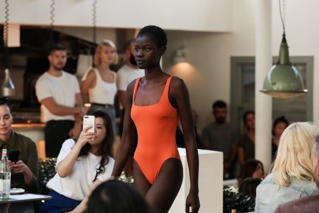 a woman in an orange swimsuit is walking in front of a crowd
