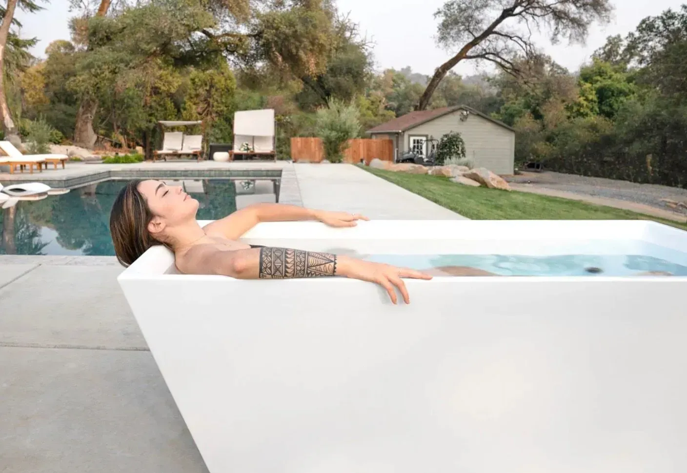 a woman is laying in a bathtub next to a pool .