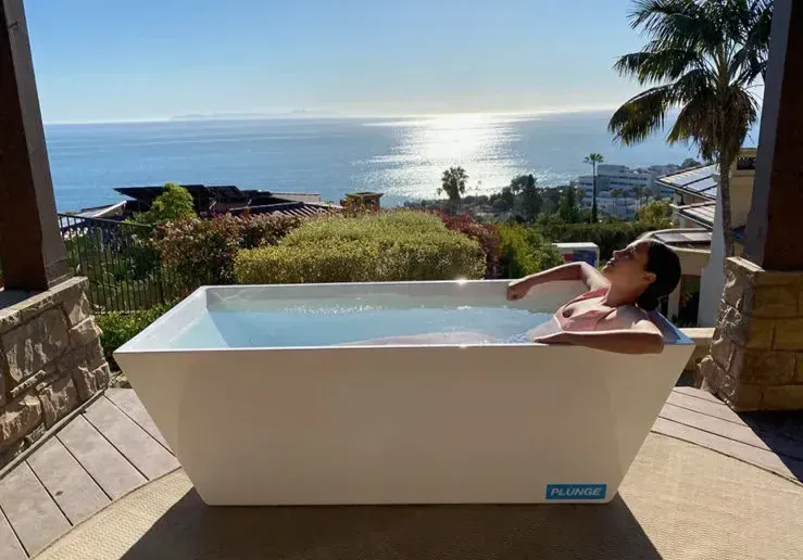 a woman is laying in a bathtub with a view of the ocean .