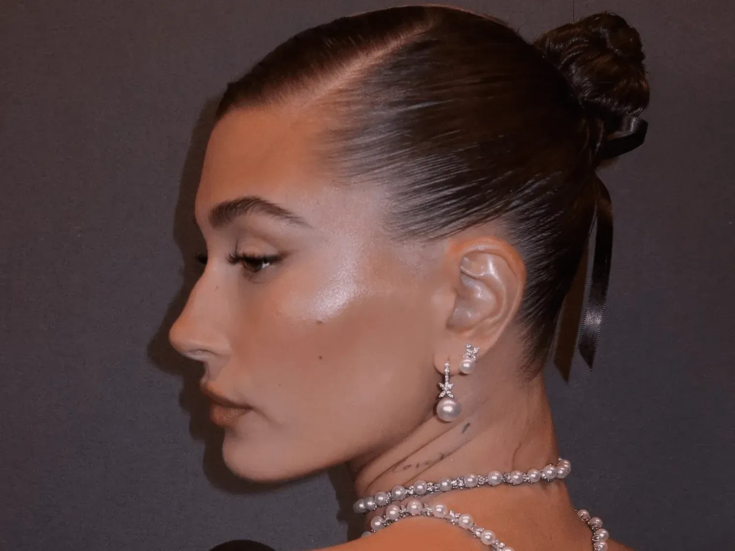 a close up of a woman wearing a bun and pearls .