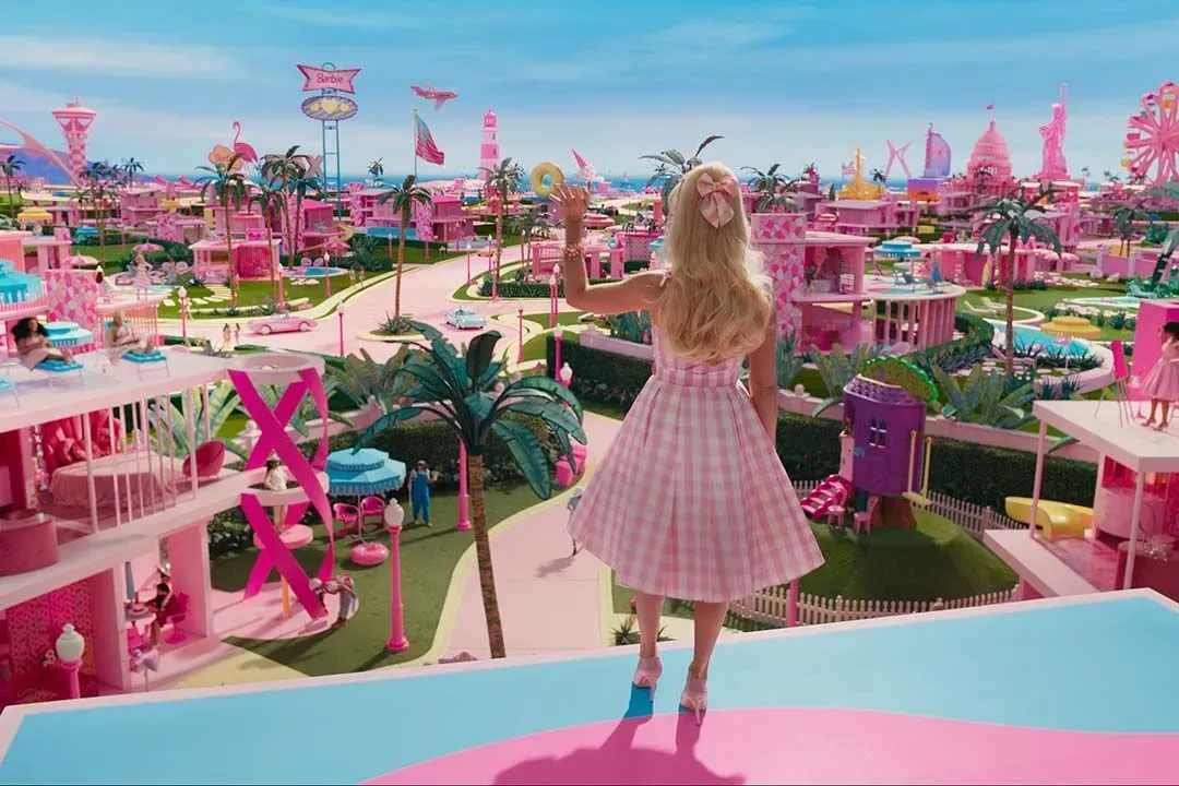 a woman in a pink dress is standing on a balcony overlooking a pink city .