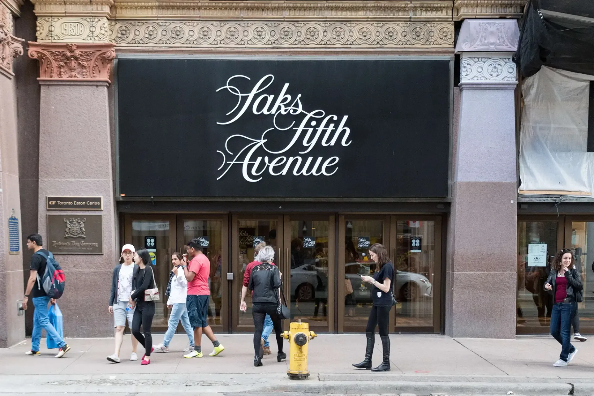 a group of people are walking in front of saks fifth avenue