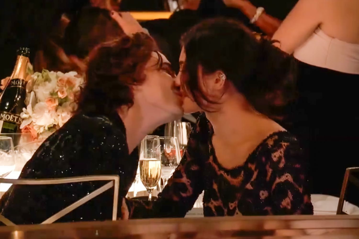 a man and a woman are kissing while sitting at a table .
