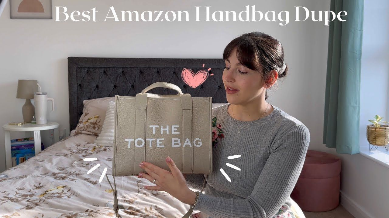 a woman is holding a tote bag in front of a bed .