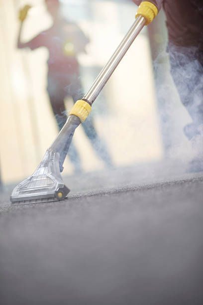 A person is using a vacuum cleaner to clean a carpet.