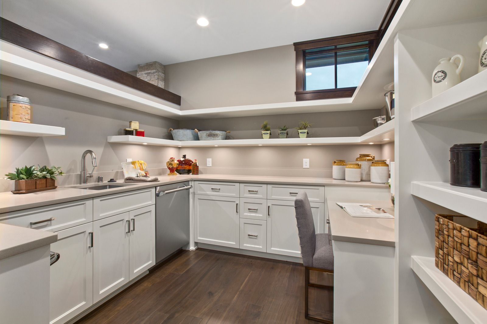 Bright modern pantry kitchen with white shelves, cabinets, countertop, and dark wood floor