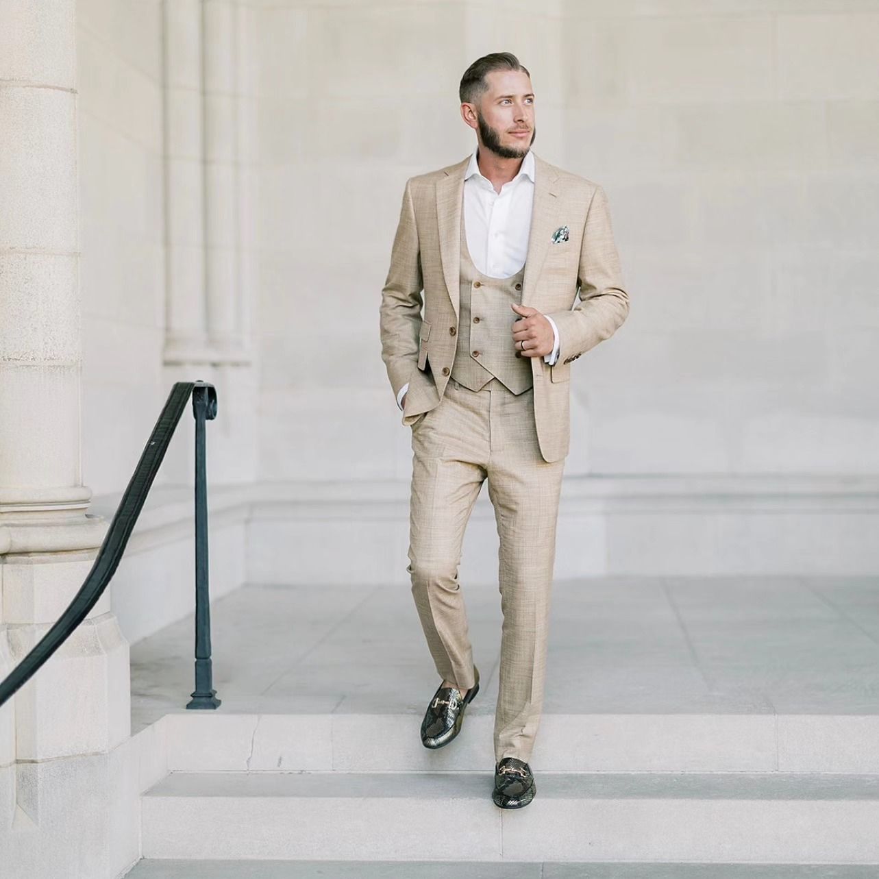 A man in a tan suit is walking down stairs.