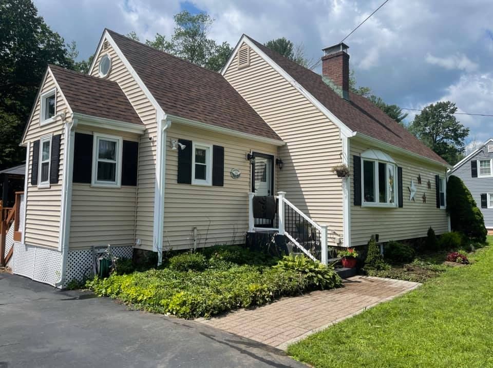 A house with a brown roof and black shutters is for sale.