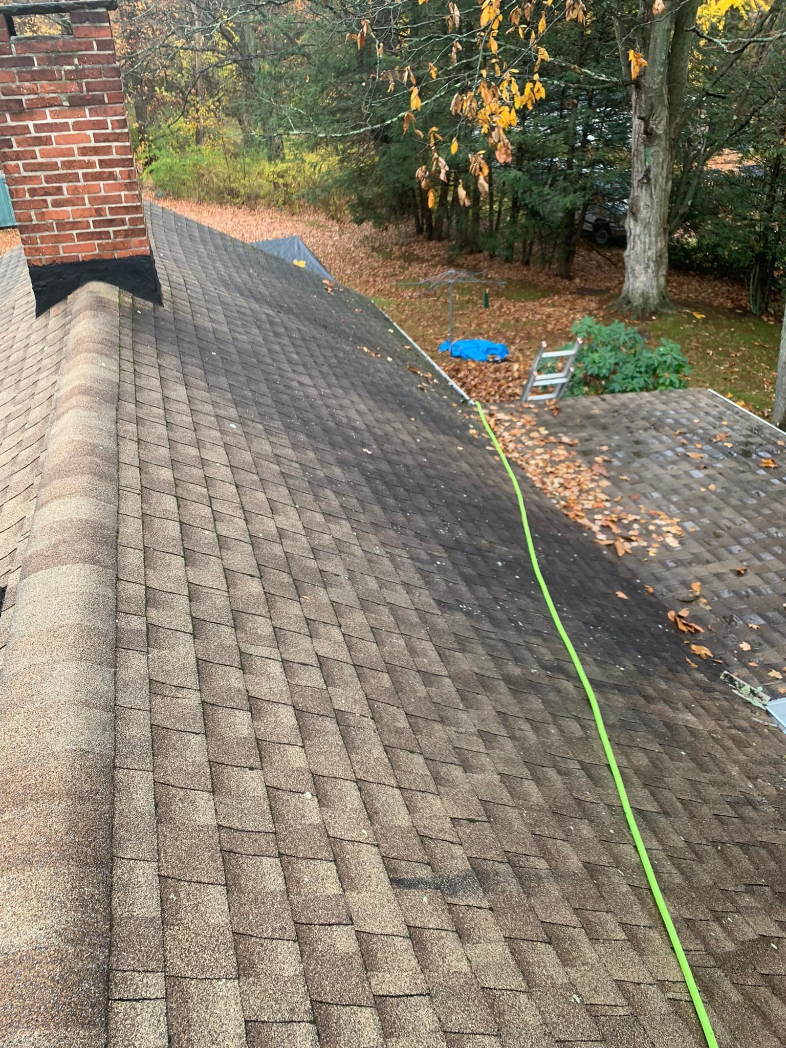 A roof with a green hose attached to it and a chimney on it.