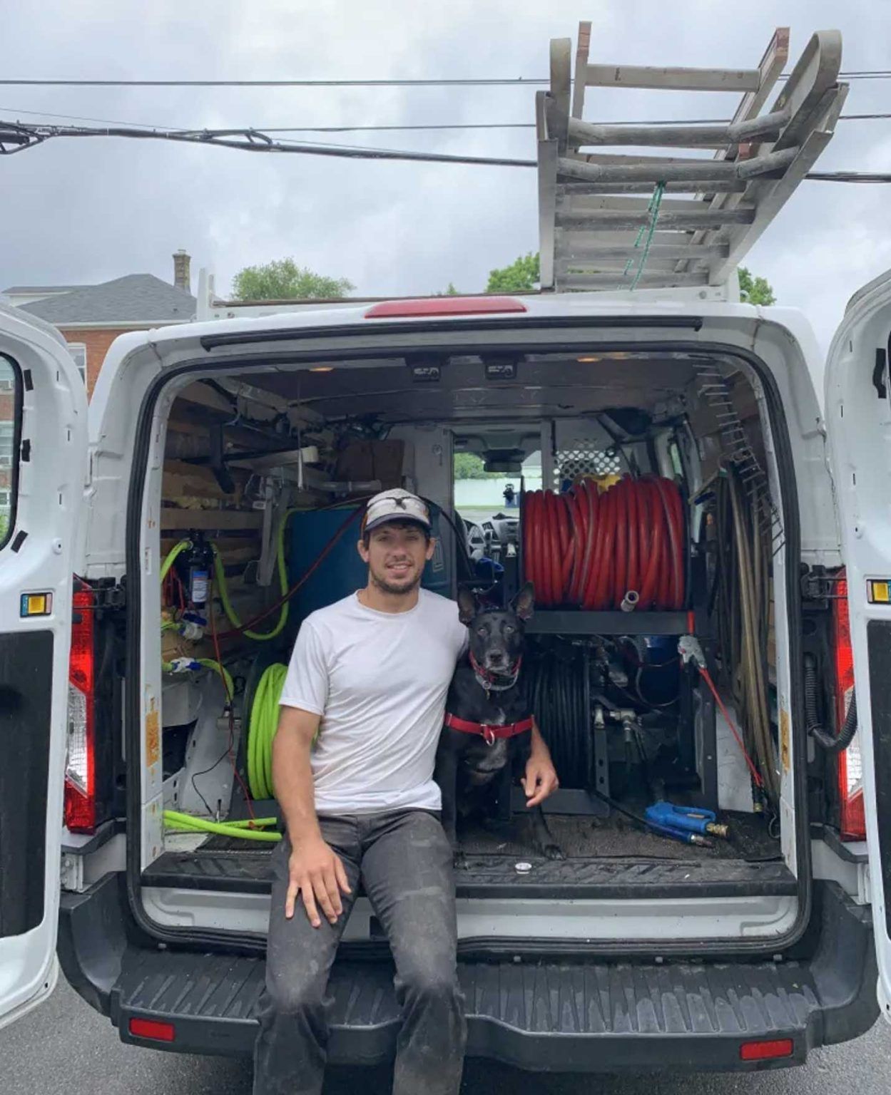 A man and a dog are sitting in the back of a van.