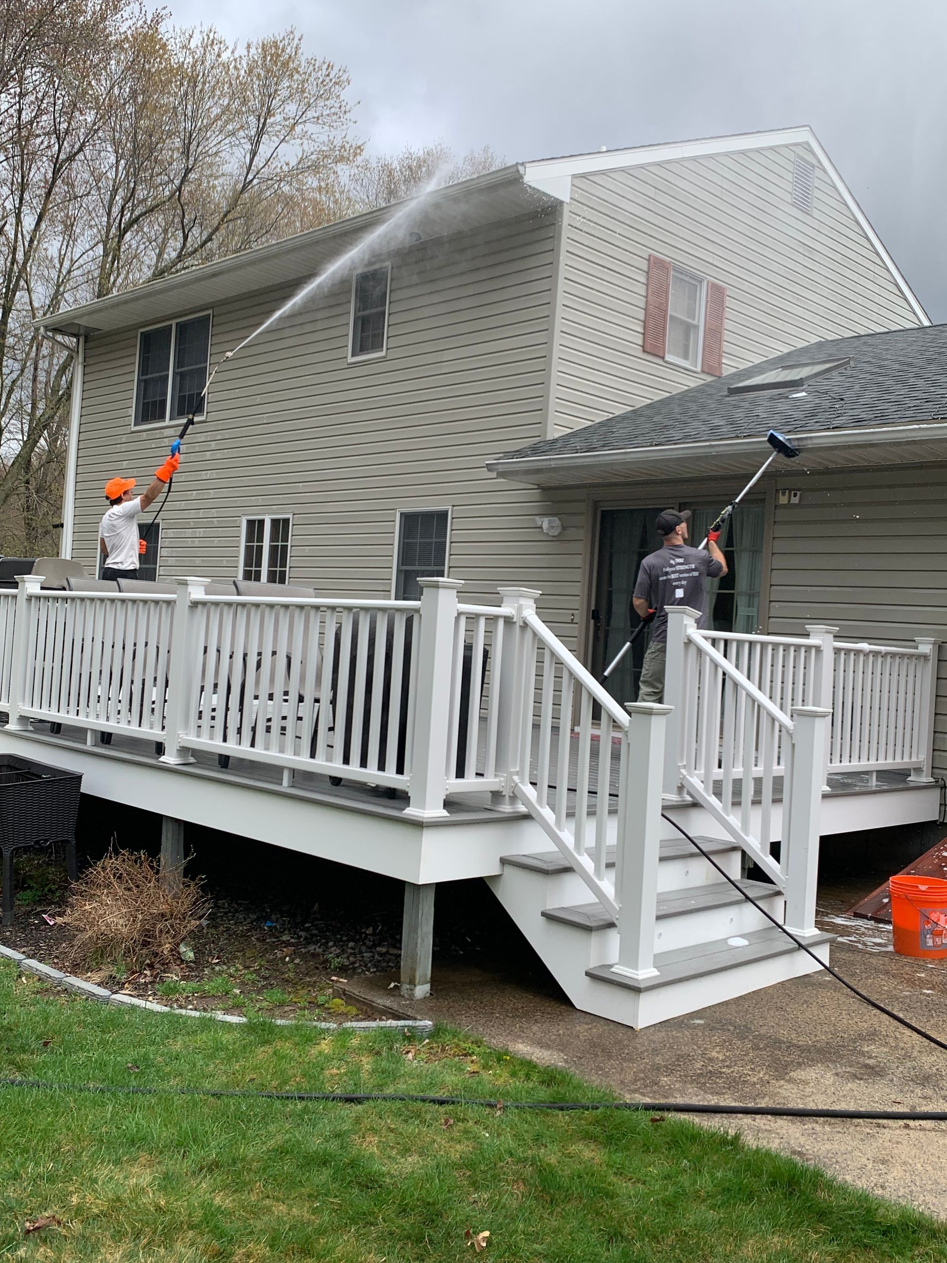 A man is cleaning the side of a house with a pressure washer.