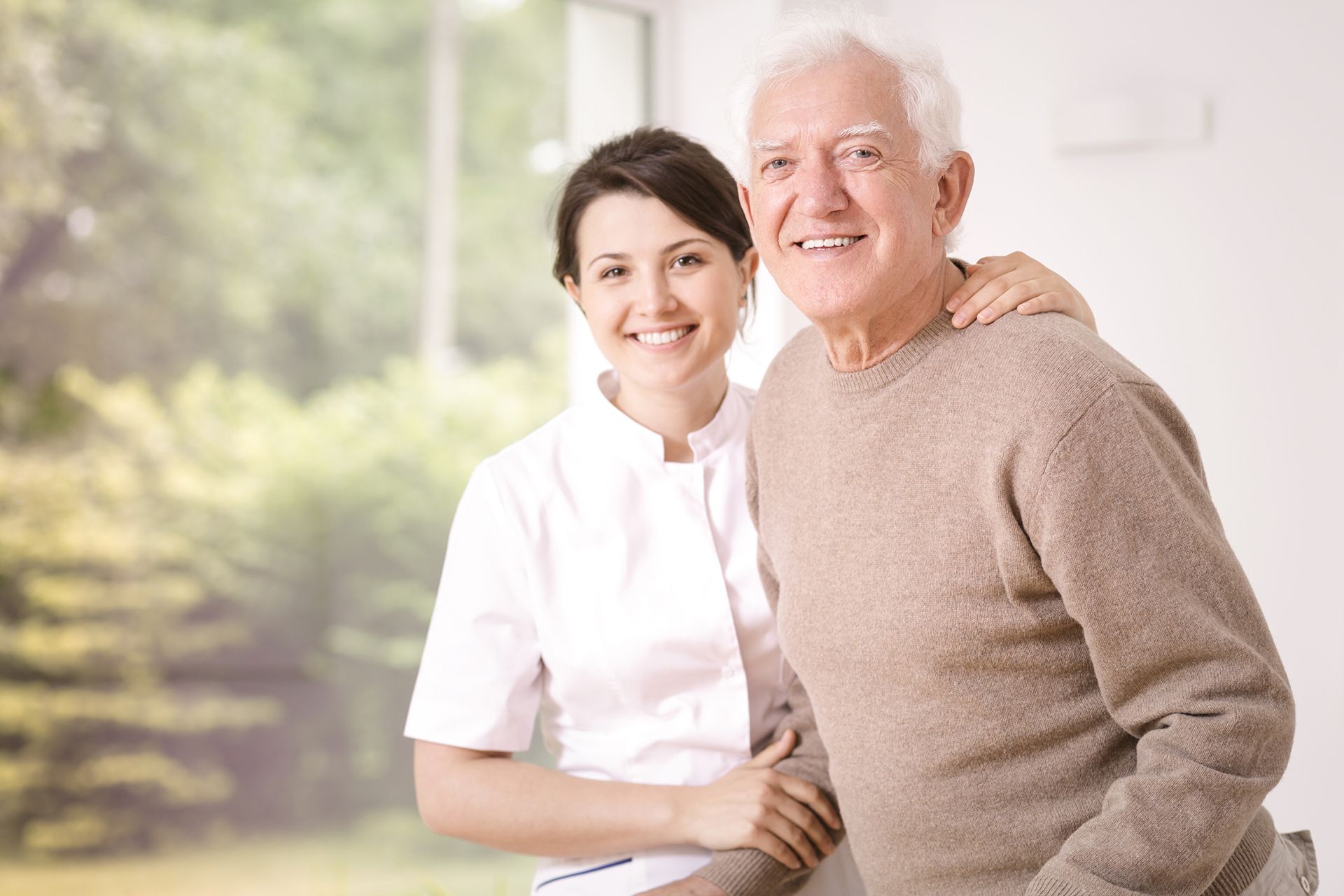 friendly smiling caregiver hugging happy elderly