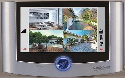 Pannello di controllo del sistema di sicurezza che visualizza i feed delle telecamere in tempo reale da varie aree di una casa, con cornice argentata e interfaccia touchscreen.
