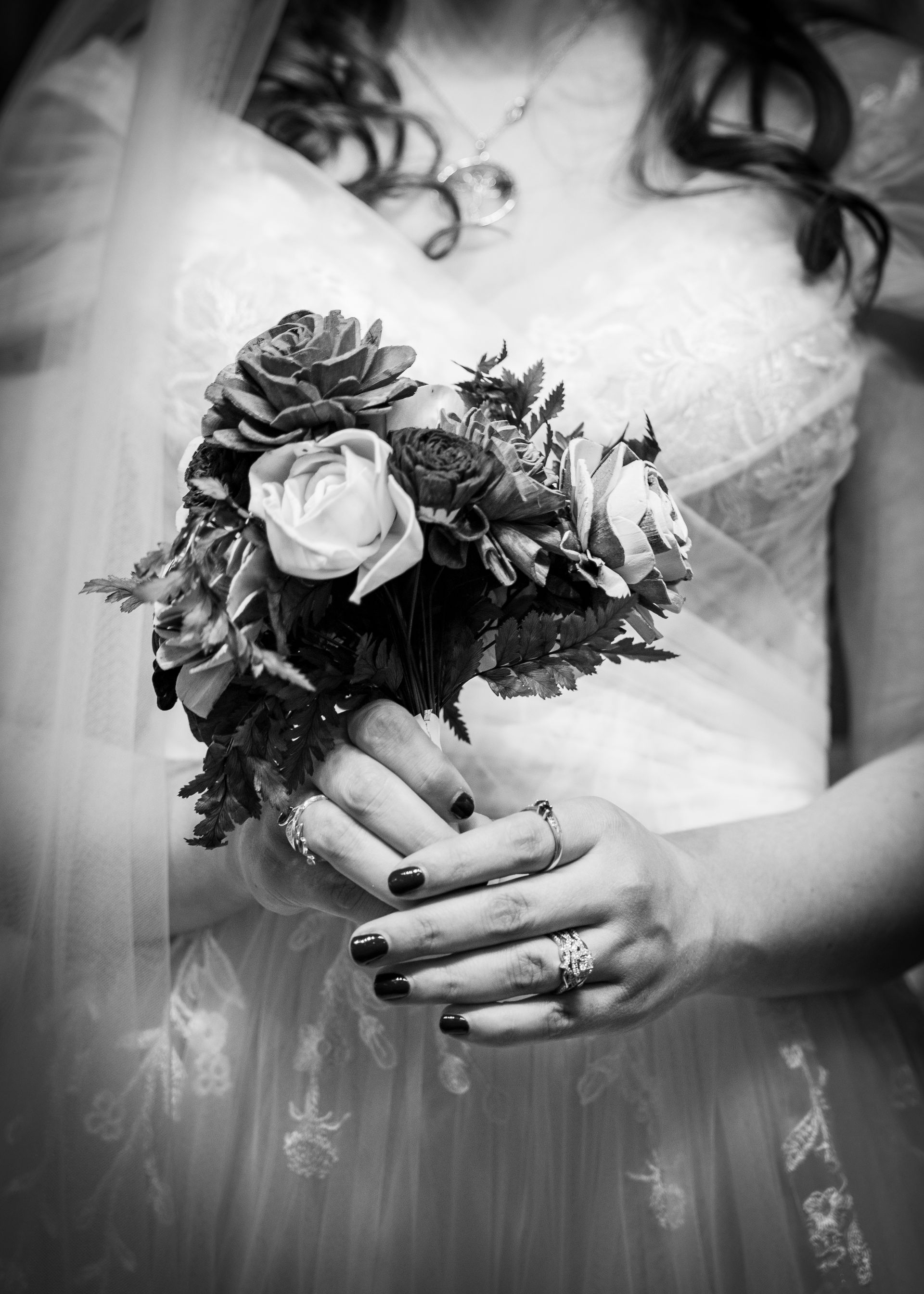A black and white photo of a bride holding a bouquet of flowers.