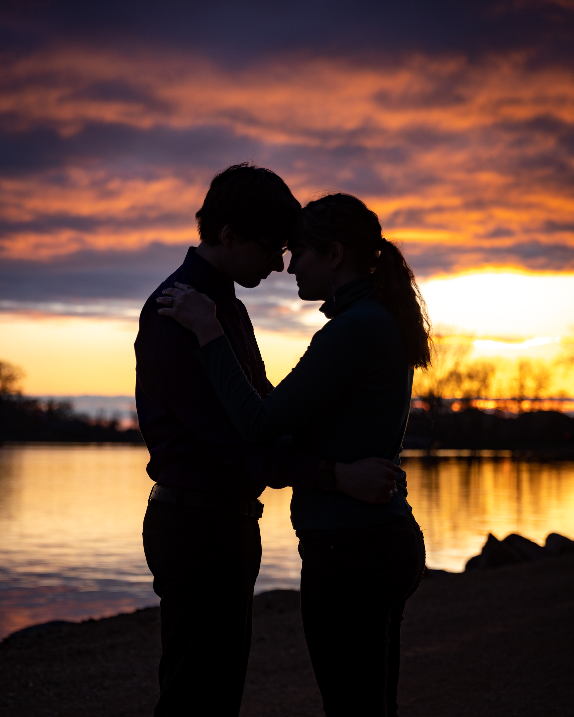 A silhouette of a man and woman hugging at sunset