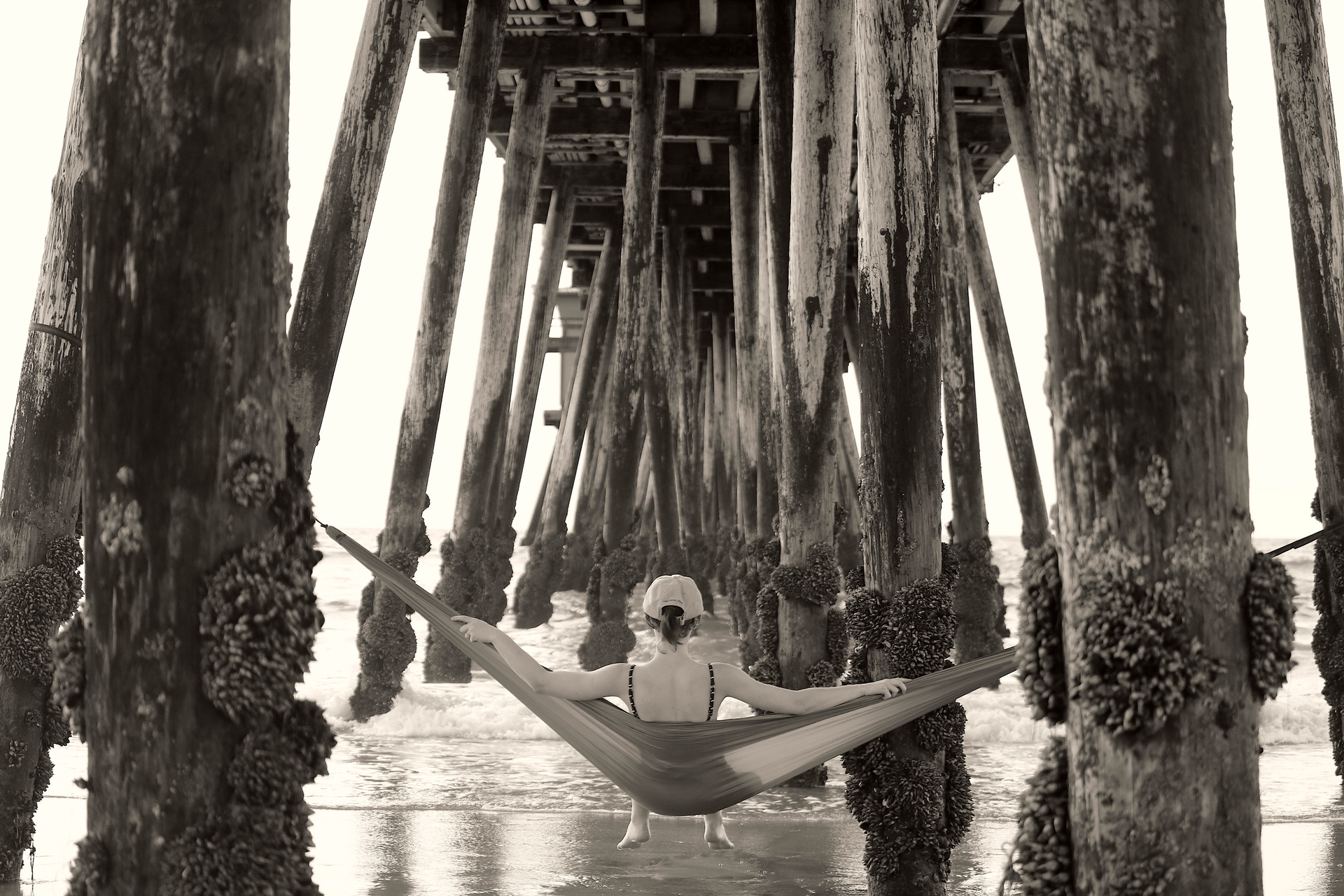 A person is laying in a hammock under a pier.