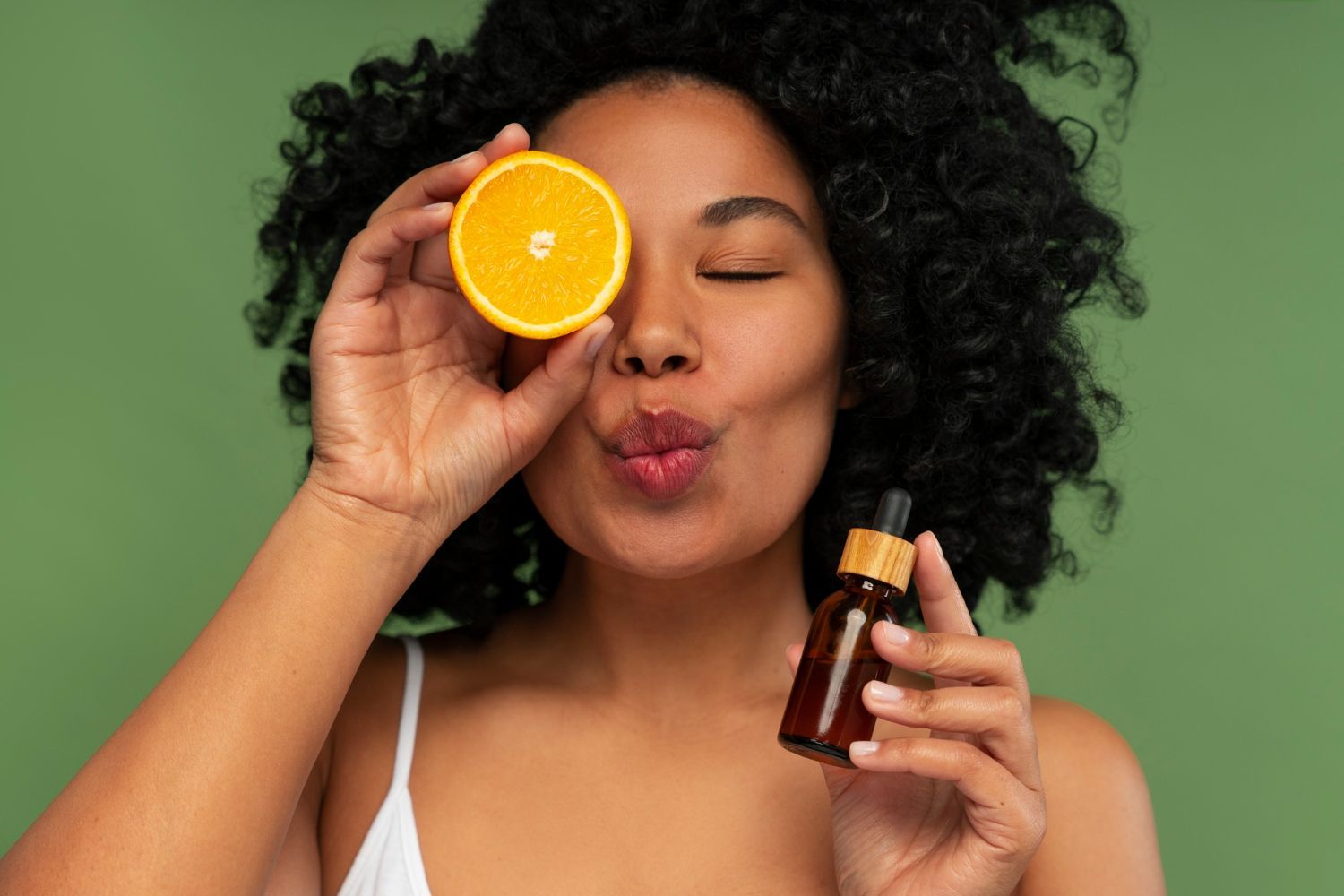 Mulher segurando meia laranja e frasco de sérum, simbolizando vitamina C no skincare.