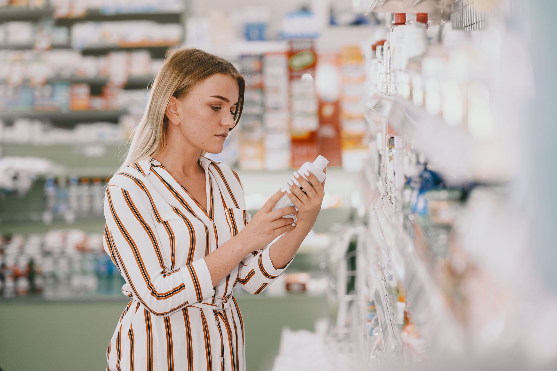 Mulher observando produto na prateleira de loja com atenção ao rótulo