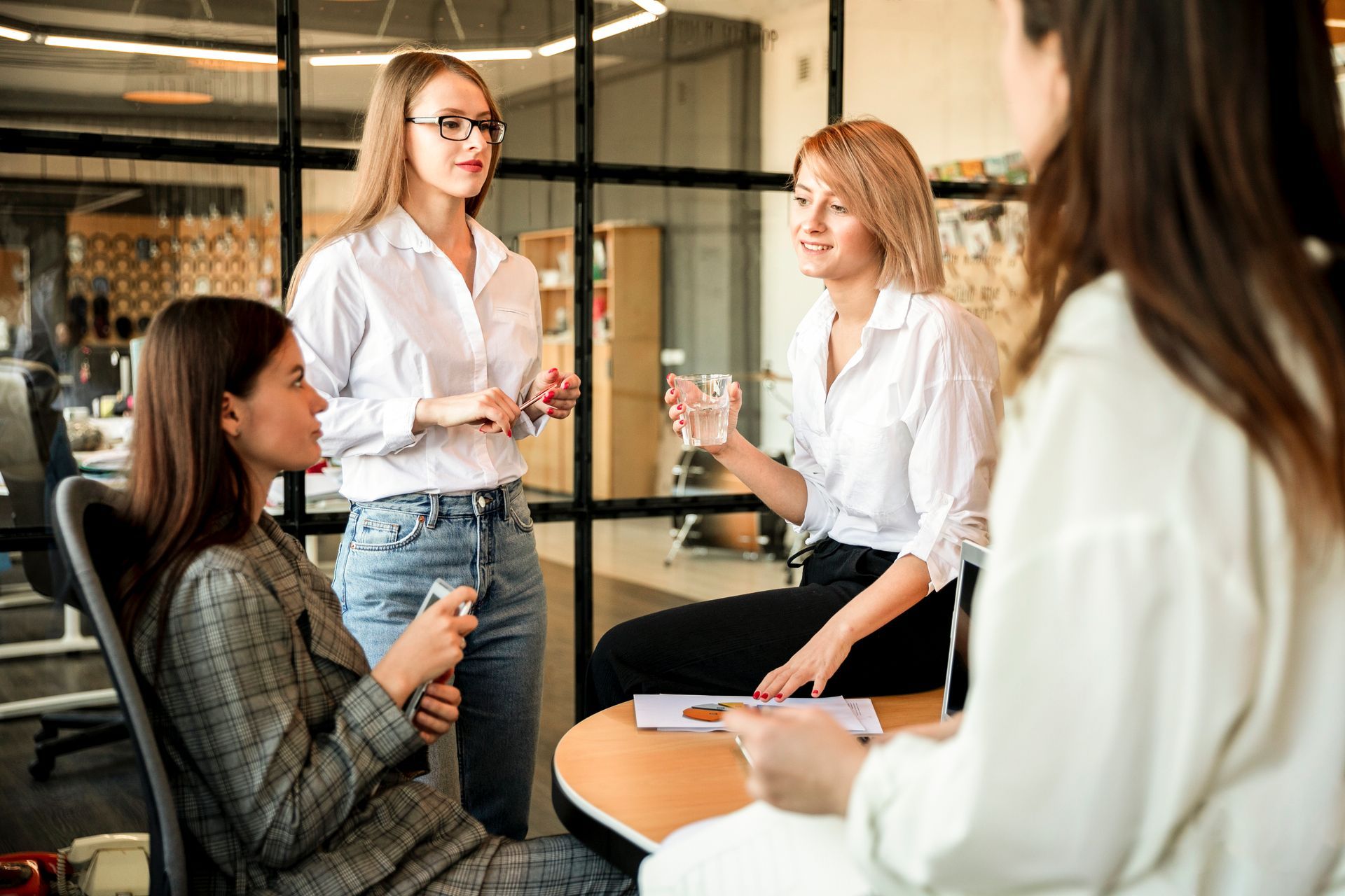 Grupo de mulheres em reunião discutindo estratégias de negócios em escritório moderno.