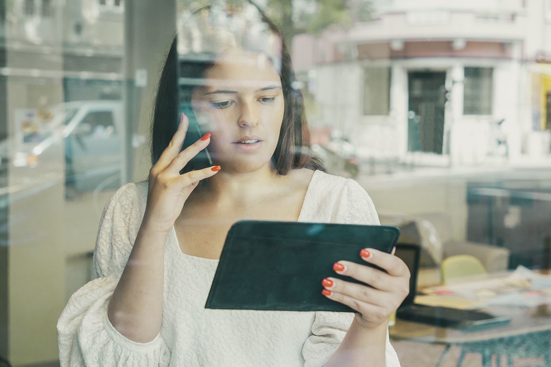 Mulher no celular e analisando dados de revenda de cosméticos com inteligência artificial em tablet.