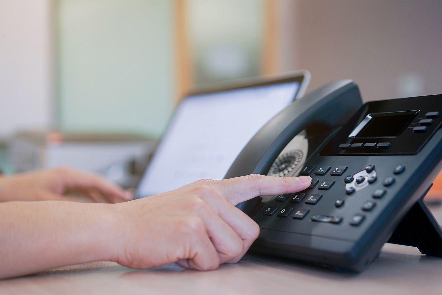 Person dialing on a black office phone Person dialing on a black office phone