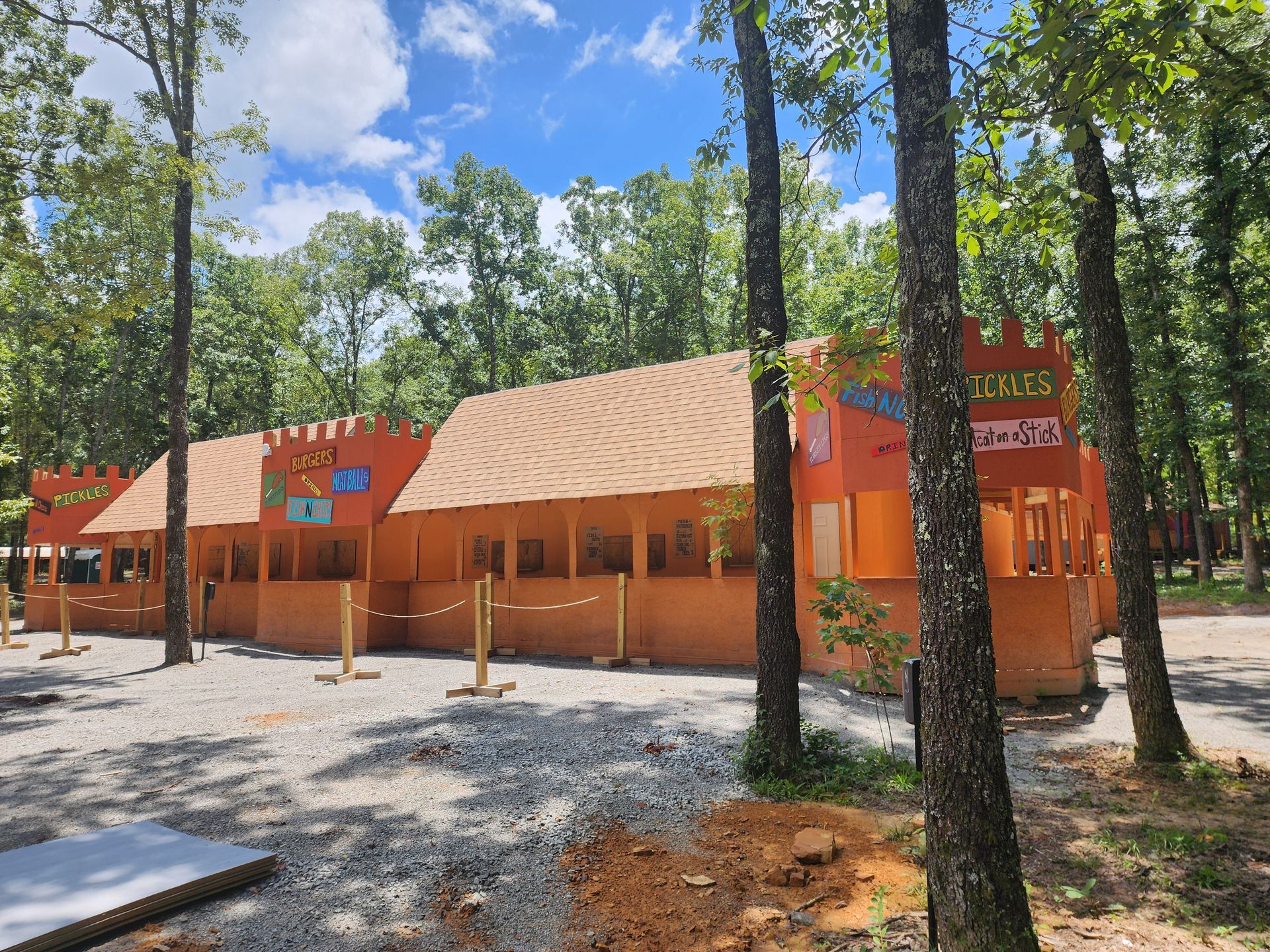 Orange building with striped awnings in a wooded park, under a bright blue sky