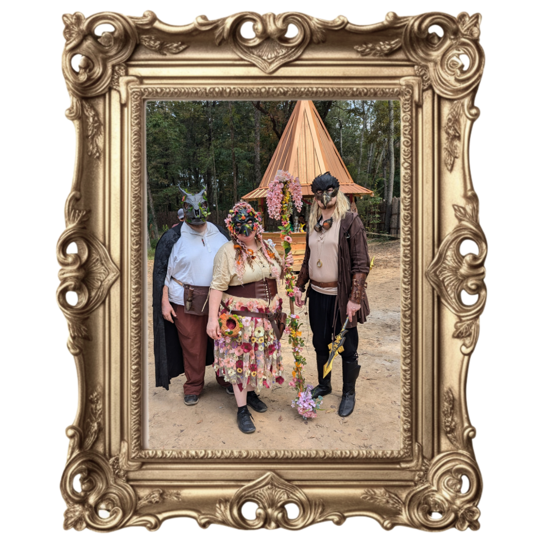 Three people stand outdoors in ornate costumes before a decorated teepee, framed in gold.