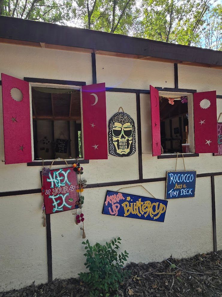 Building with red shutters, signs reading "Hex," "Racoon's Tea Deck," and "Buttercup." Skull art.