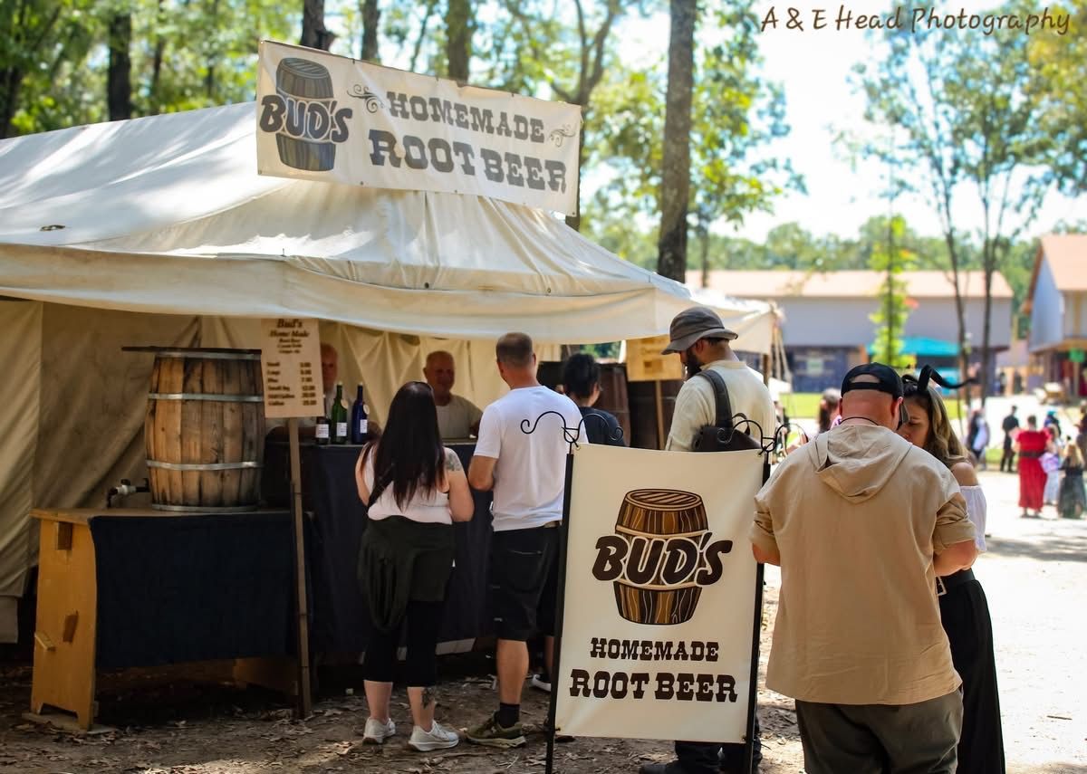 People at a Bud’s Gourmet Root Beer stand under a white canopy in a sunny outdoor market