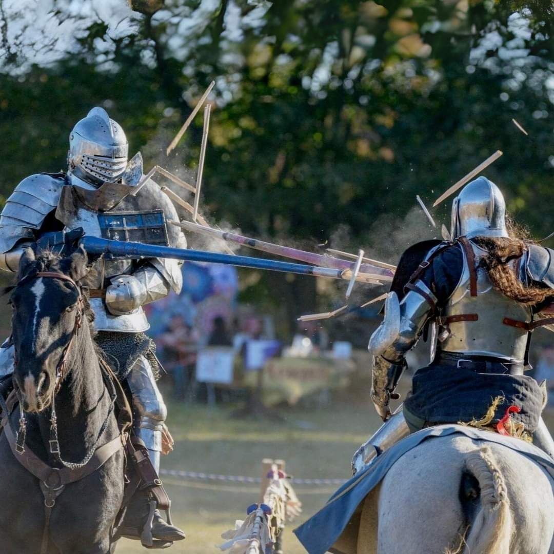 Two armored knights on horseback joust with lances in a medieval reenactment