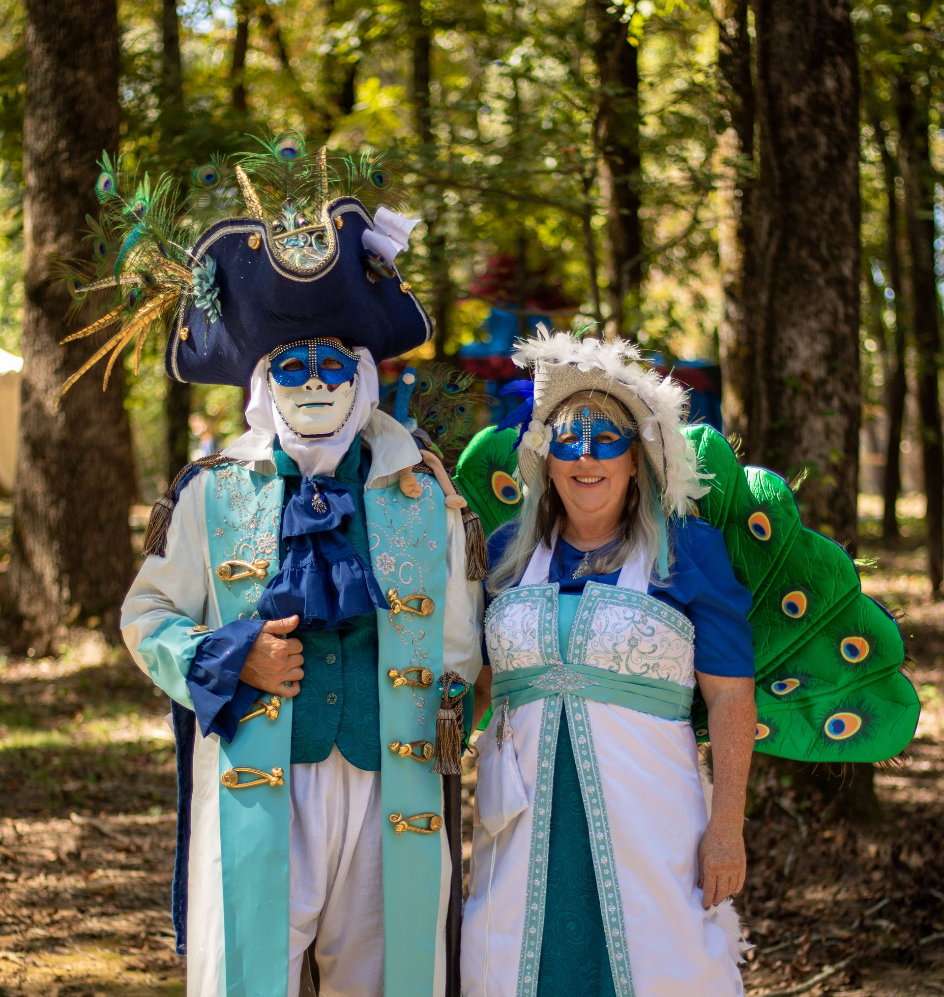 Two people in colorful pirate costumes posing outdoors in a wooded park