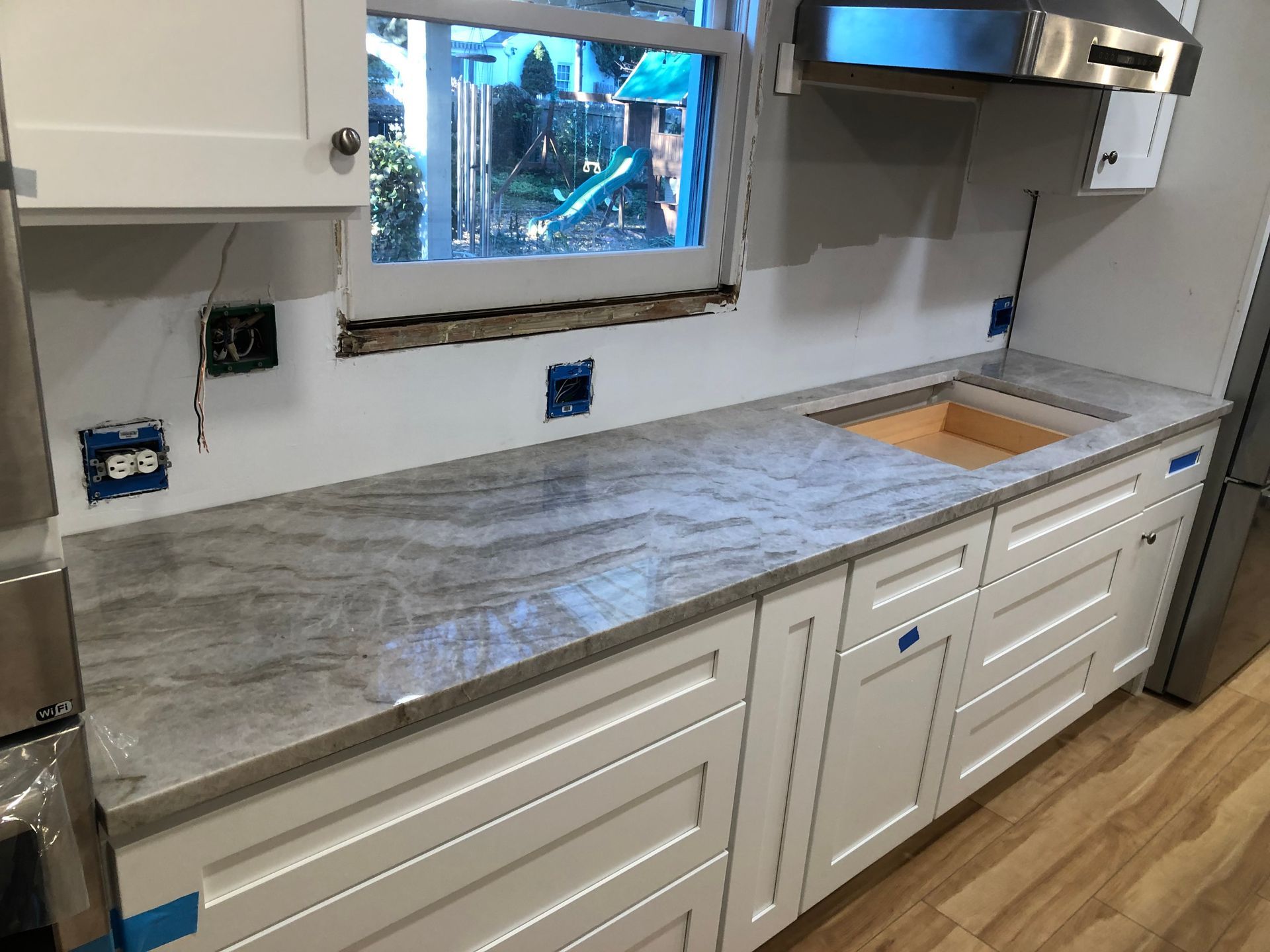 Kitchen countertop with white cabinets and a sink cutout; gray granite countertop.