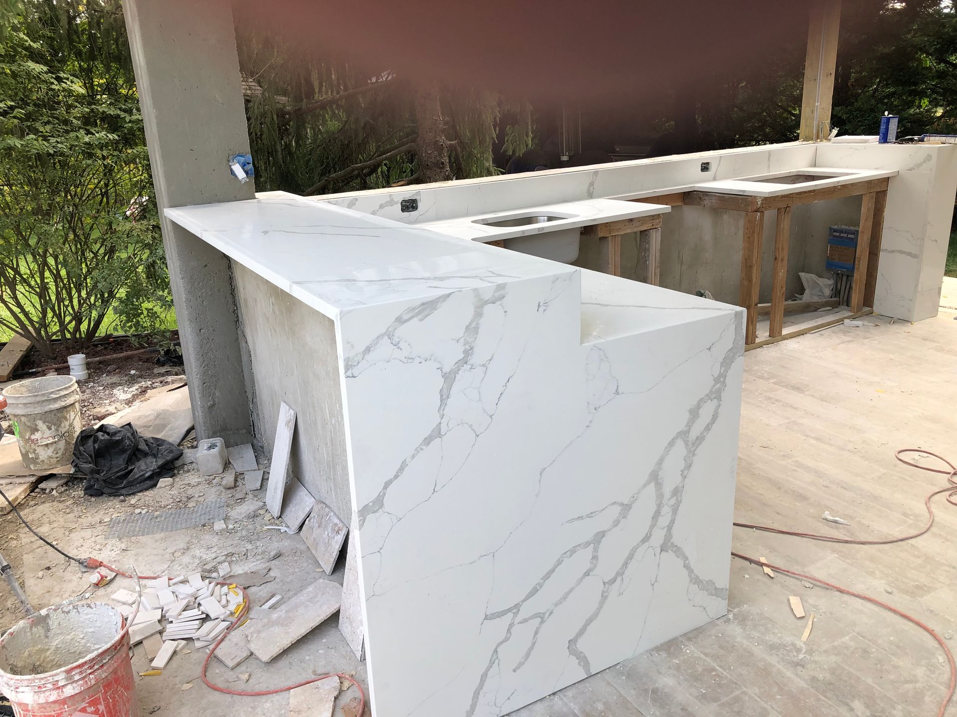 Outdoor kitchen under construction; white countertop with gray veining, concrete base.