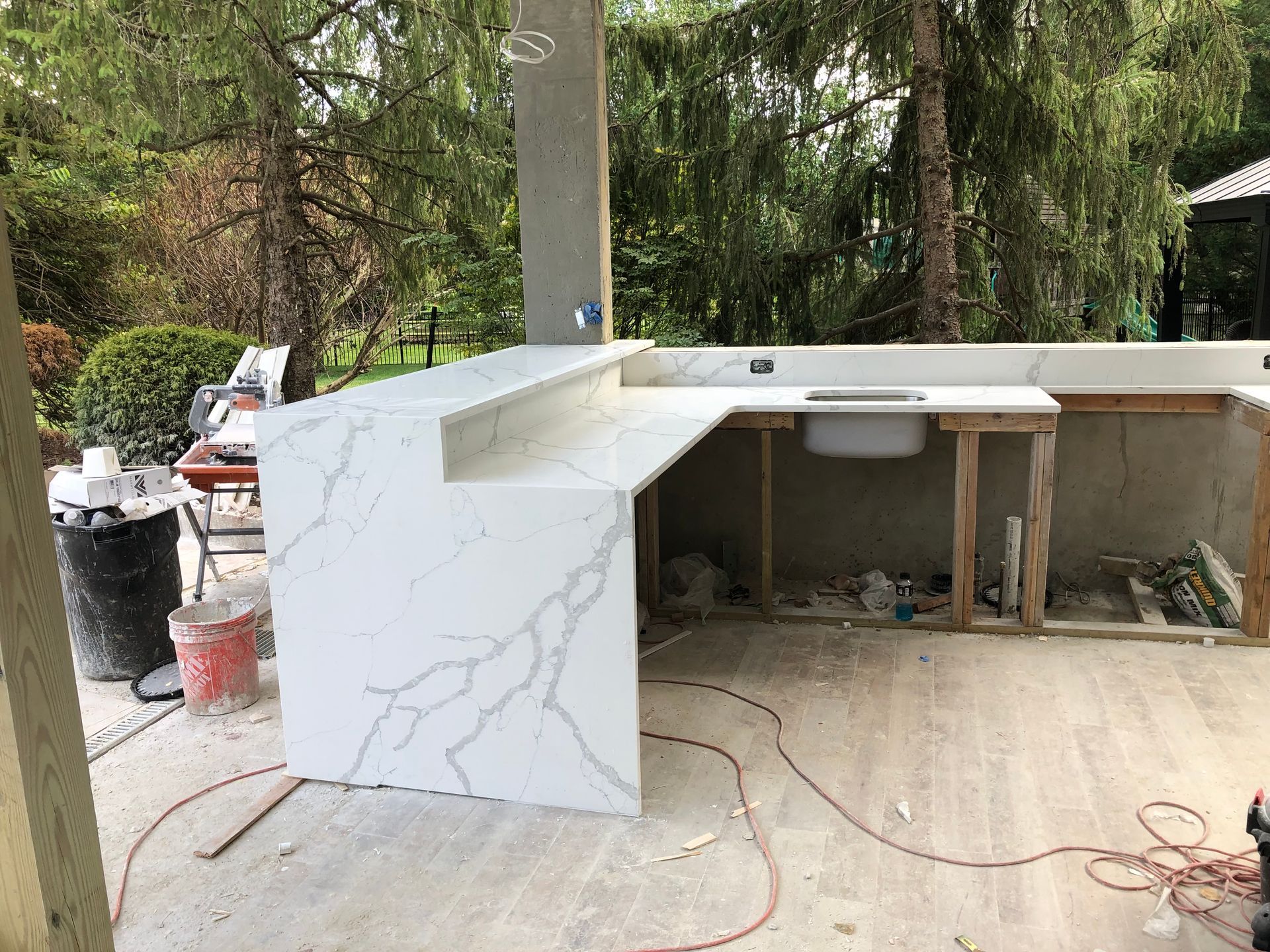 Outdoor kitchen with white quartz countertop, unfinished wood frame, and sink.