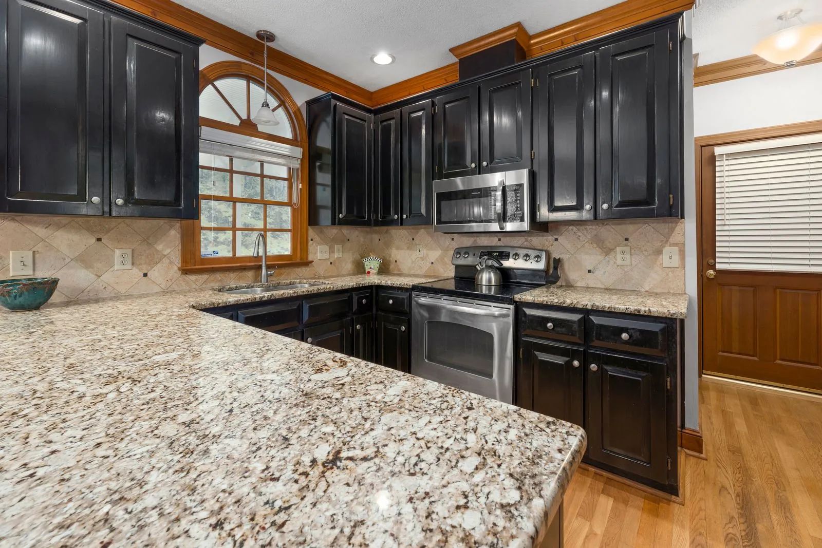 Modern kitchen with dark cabinets, granite countertops, stainless appliances, and wood flooring