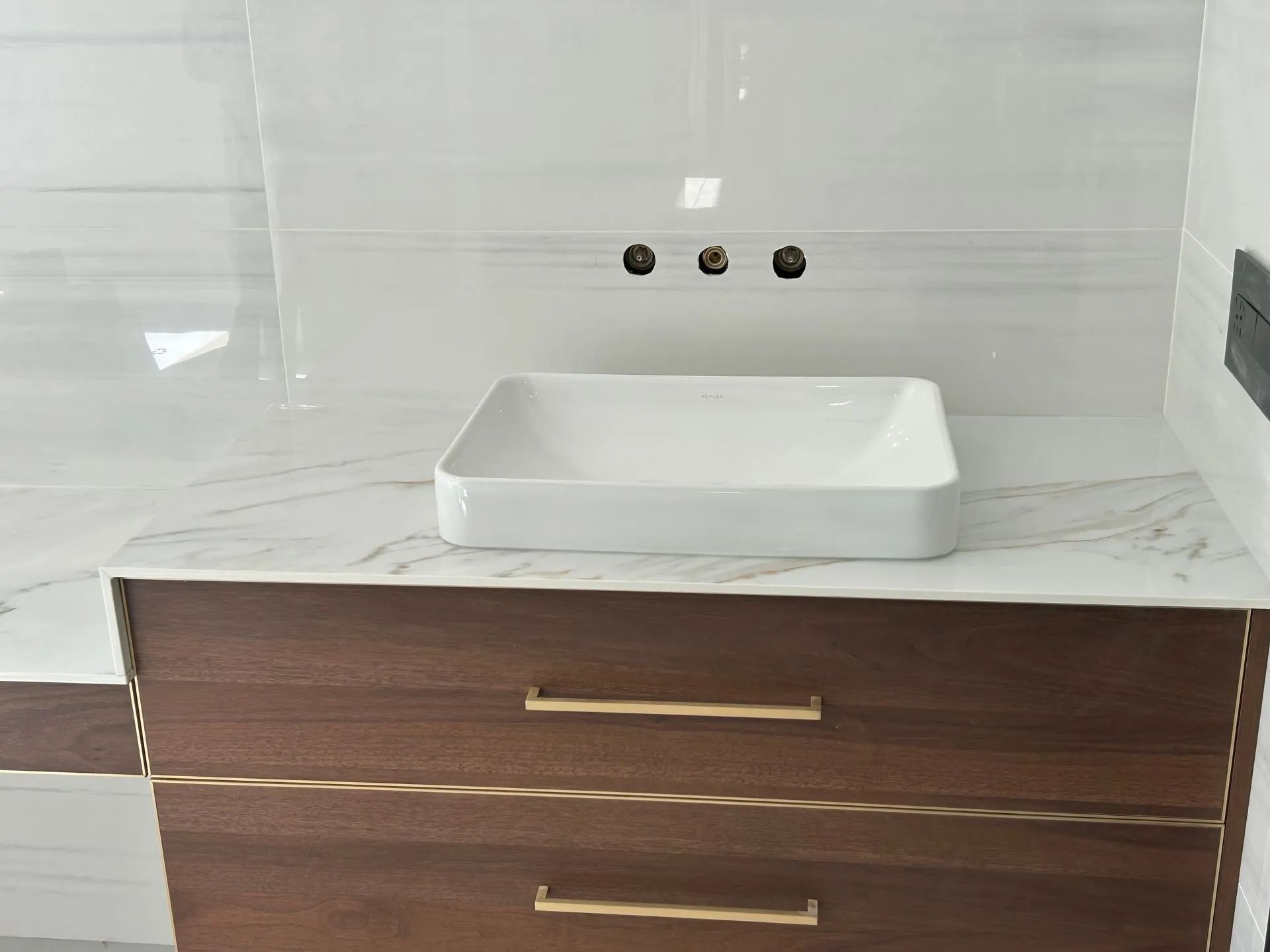 Modern bathroom vanity with white vessel sink, wall faucet, and dark wood drawers