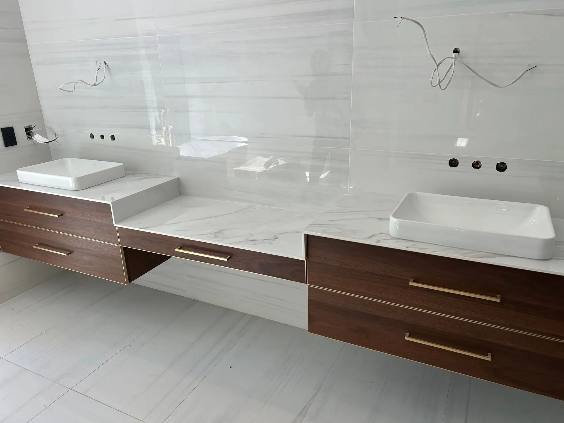 Modern double vanity with two sinks, dark wood drawers, and white marble countertop in a bathroom