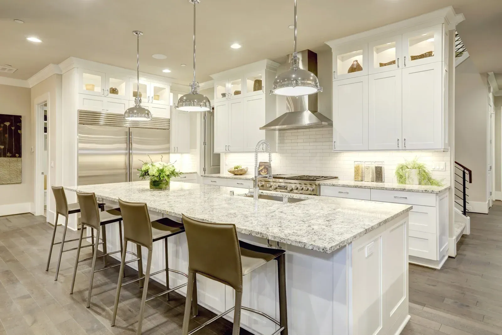 A kitchen with white cabinets , granite counter tops , and stainless steel appliances.